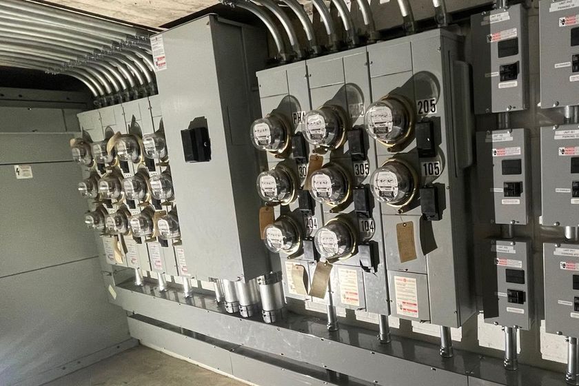 A bank of tenant meters and subpanels on a multi-unit building