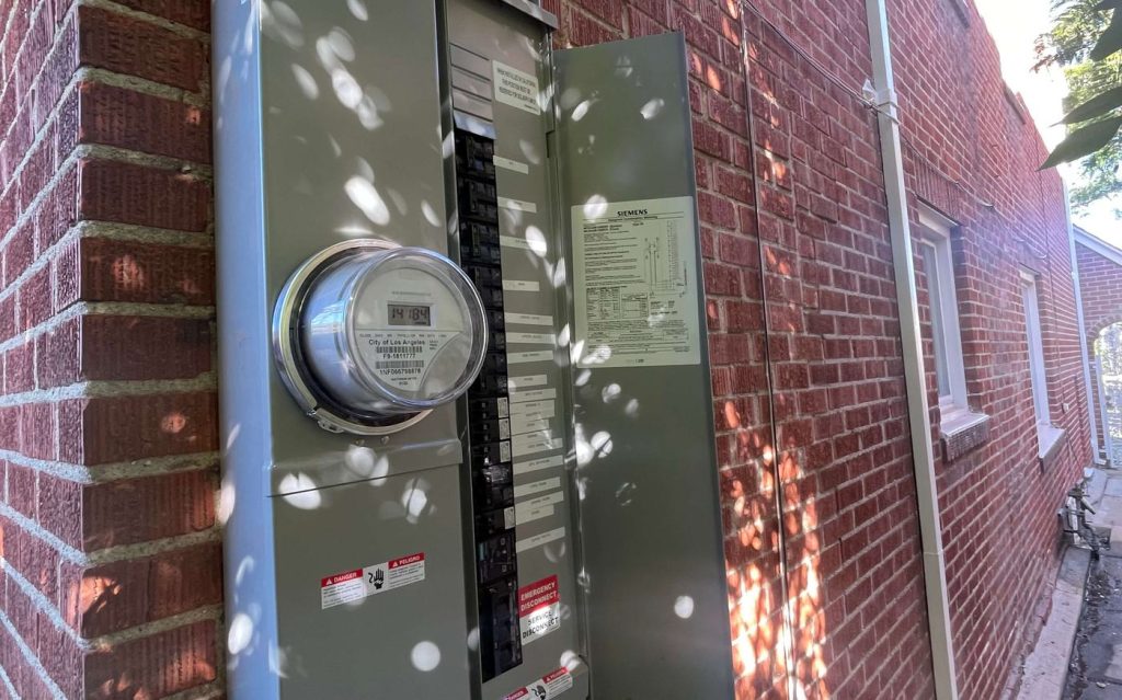 An electrical panel and meter on the side of a house